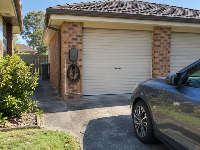Wall-mounted EV charger and coiled cable on a brick garage wall beside a driveway in Springfield